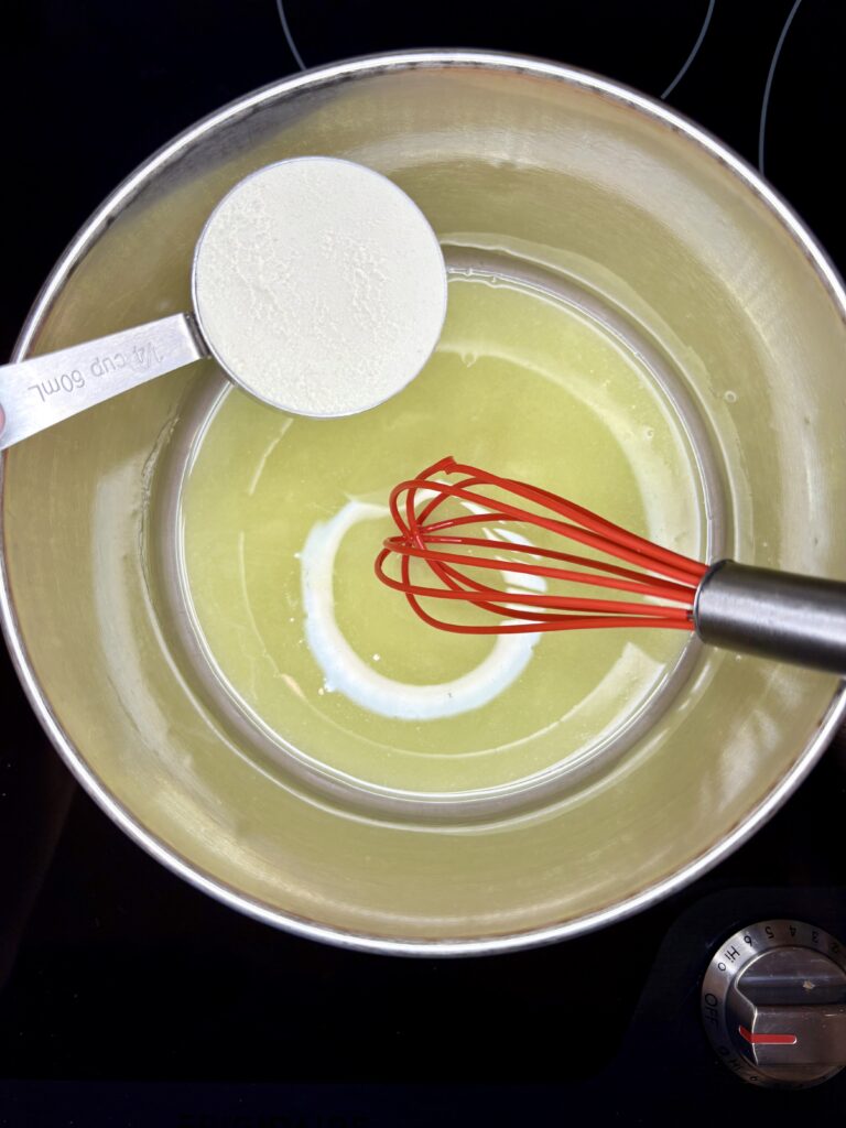 flour being added to melted butter in a sauce pan with a whisk