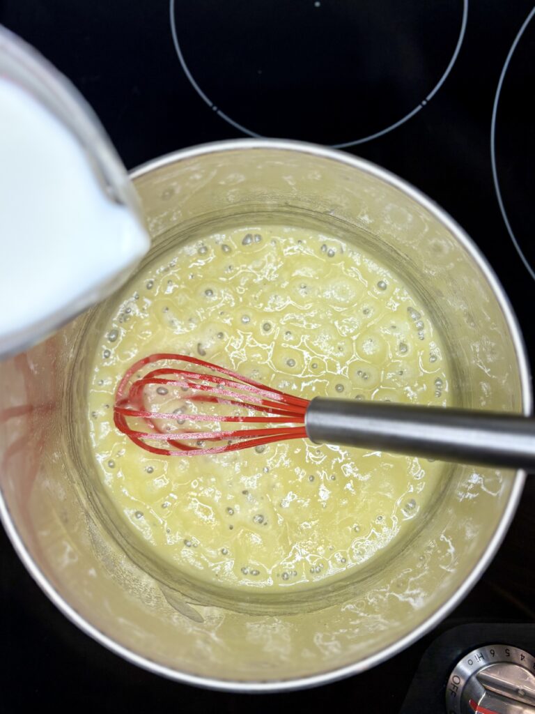 milk being poured into pot with butter and flour