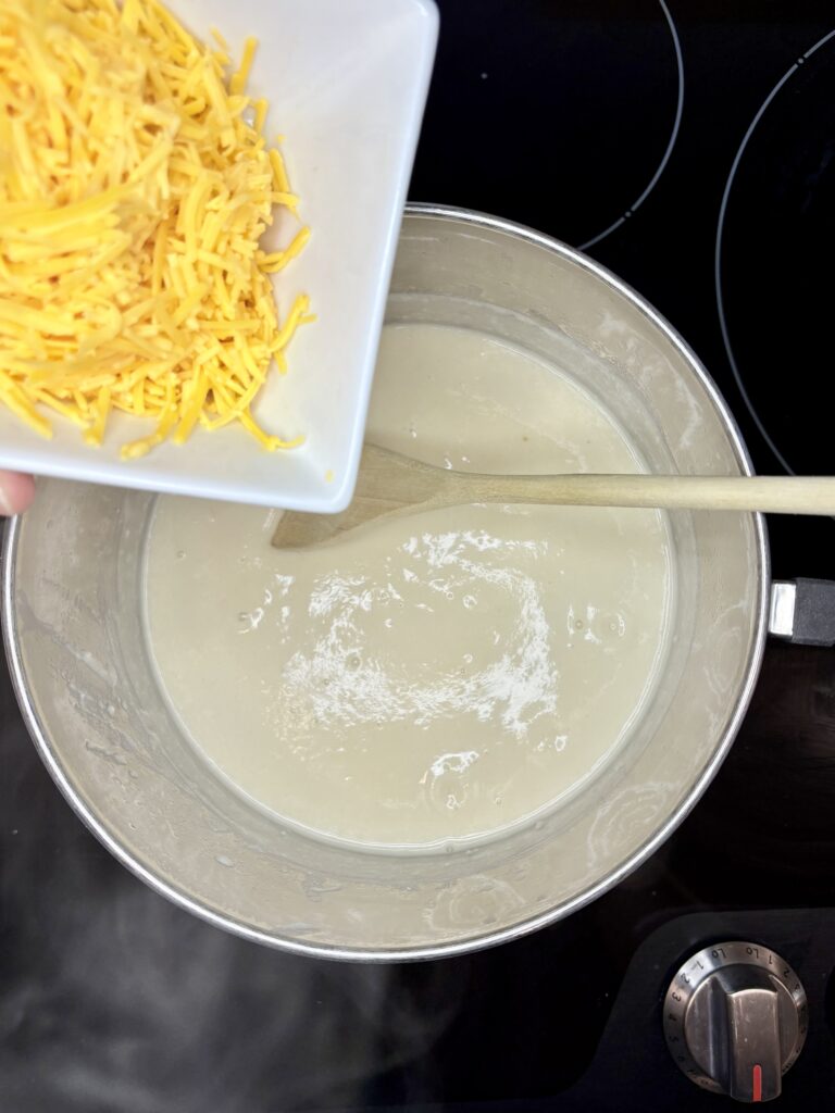 shredded cheese being stirred in to beer and milk mix