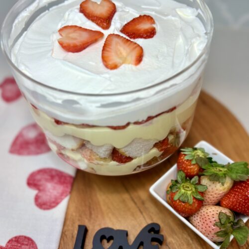 Strawberry Vanilla Trifle on a counter next to a heart towel an bowl of strawberries