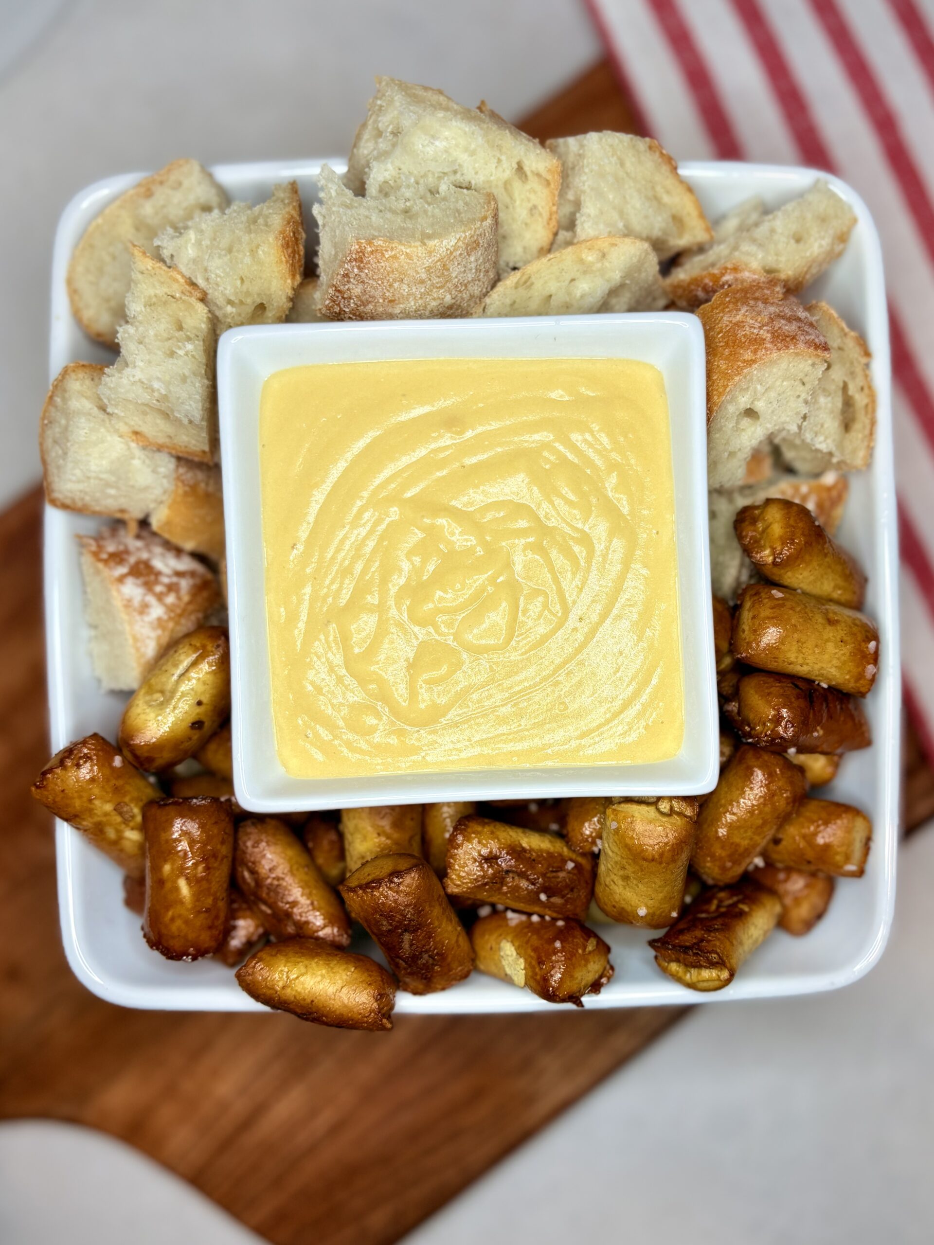 a bowl of beer cheese surrounded by pretzel bites and chunks of bread