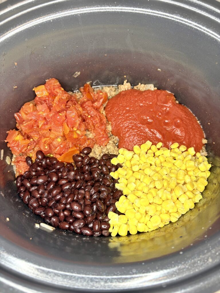 slow cooker with beef, black beans, rotten, corn, and tomato sauce