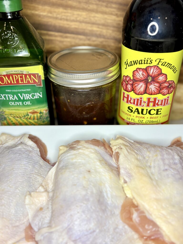 chicken on a plate next to sauce and olive oil on a counter