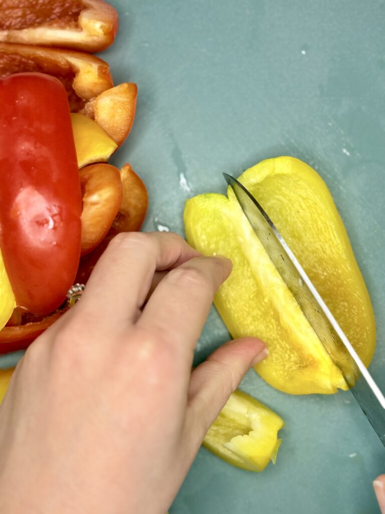 a bell pepper being sliced with a knife