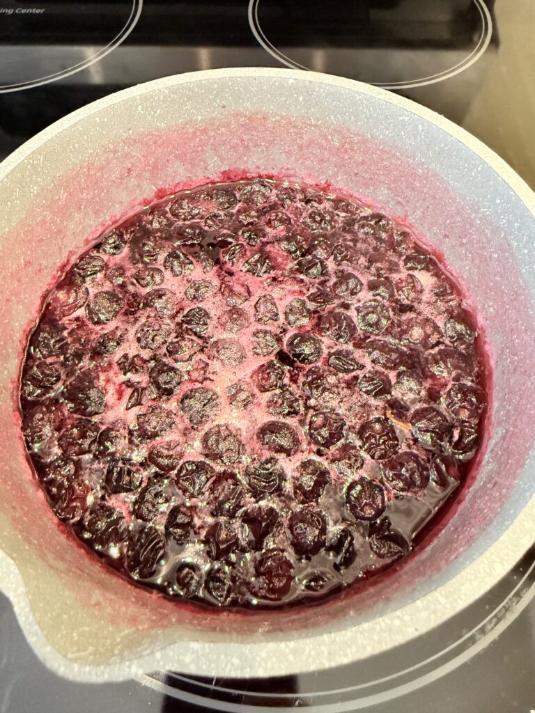 Boiling water, sugar, and blueberries on the stove top.