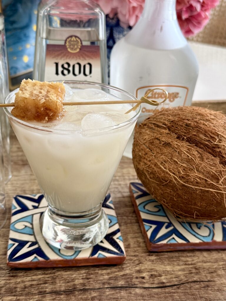 Coconut and Honey Margarita on a blue coaster on a brown tray on the counter.