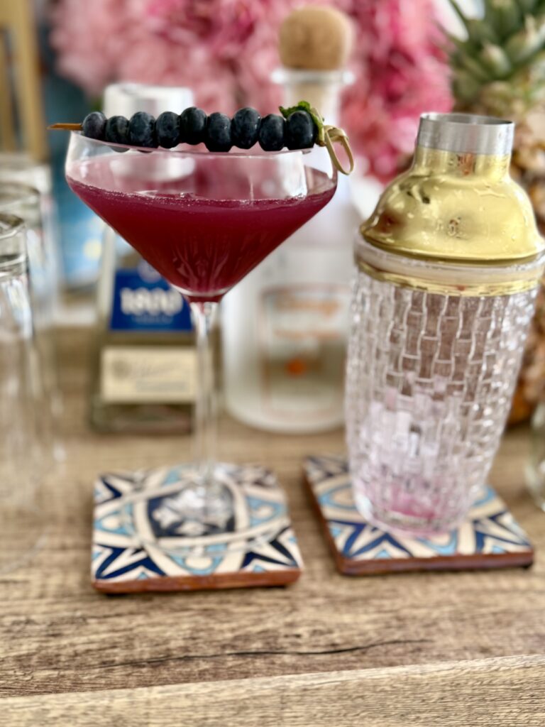 Blueberry and Pineapple Margarita on a blue coaster on a brown tray on the counter.