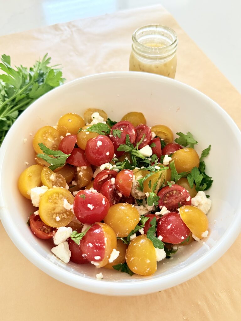 Simple tomato and feta salad in a white bowl on parchment paper paper on the counter.