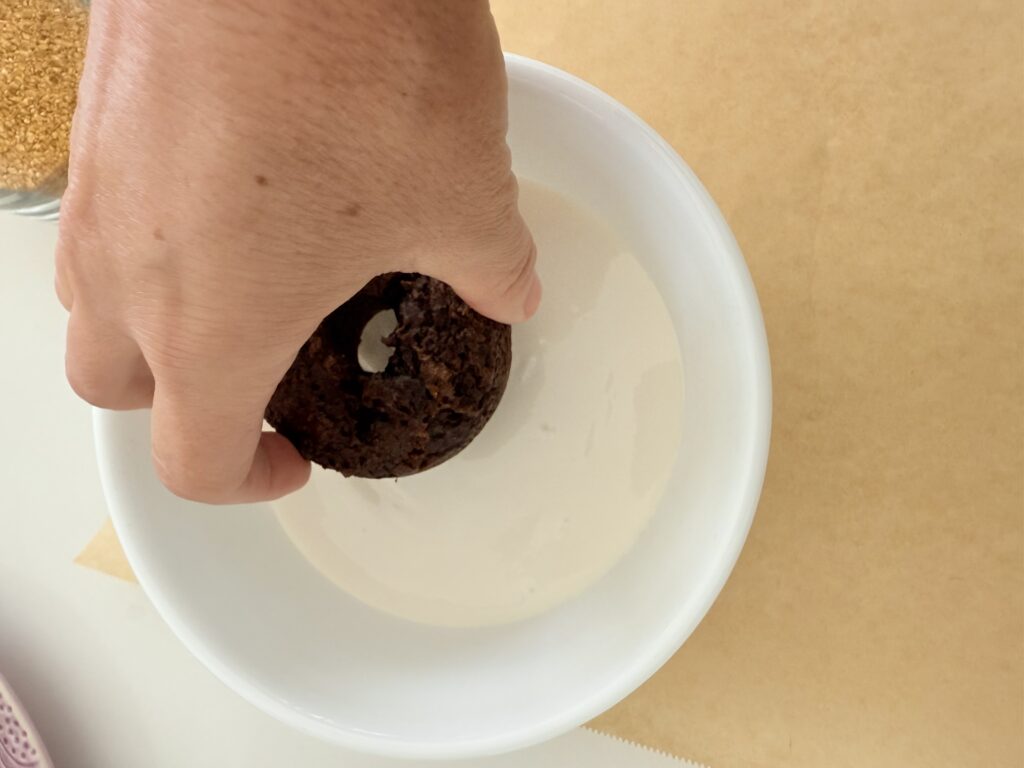 I dipped the donut into warm white icing in a white bowl on brown parchment paper on the counter.