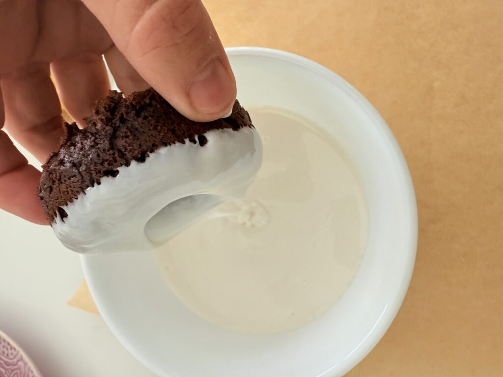 I dipped the donut into warm white icing in a white bowl on brown parchment paper on the counter.