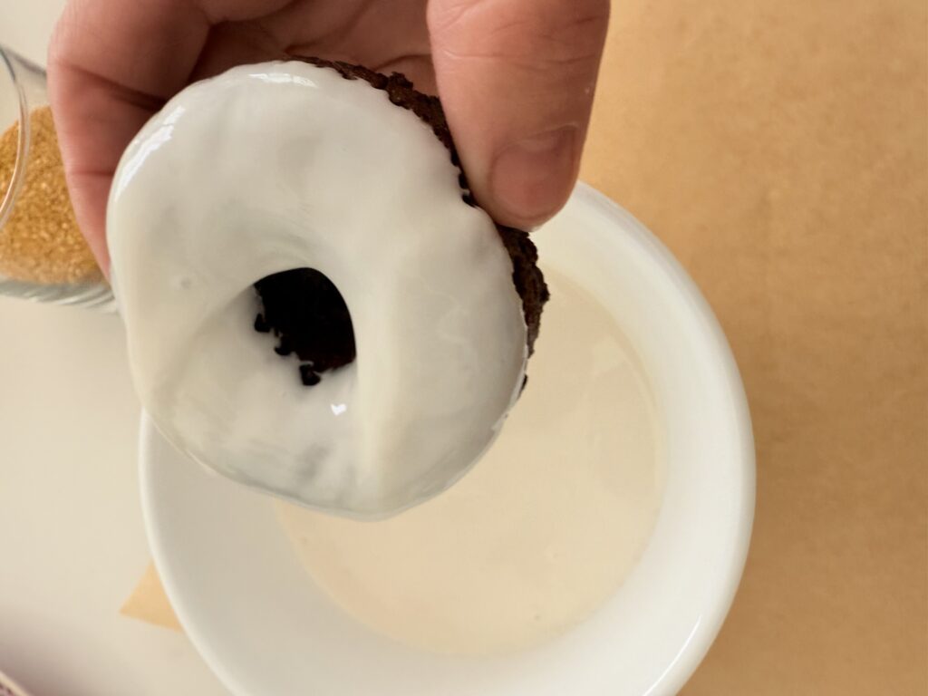 I dipped the donut into warm white icing in a white bowl on brown parchment paper on the counter.