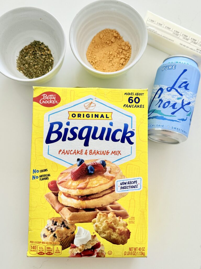 Bisquick mix, garlic powder, Italian seasoning, sparkling water and butter on the counter.