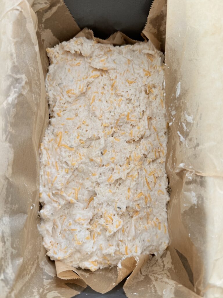 Dough in a greased and parchment paper lined 9x5 loaf pan on the counter.