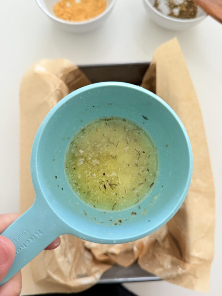 Melted butter and seasonings in a blue measuring cup.