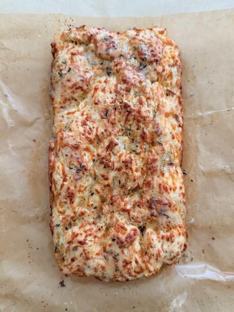 Bisquick Cheese and garlic loaf on brown parchment paper on the counter.