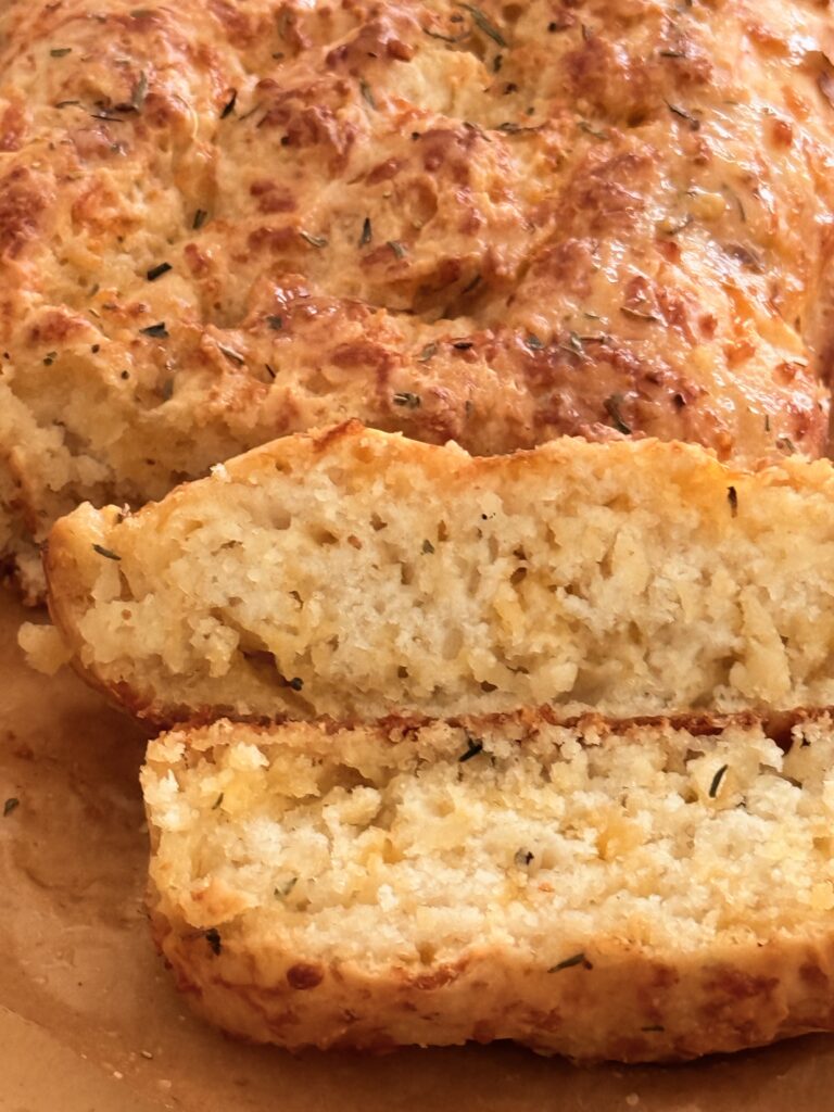 Bisquick Cheese and garlic loaf on brown parchment paper on the counter.