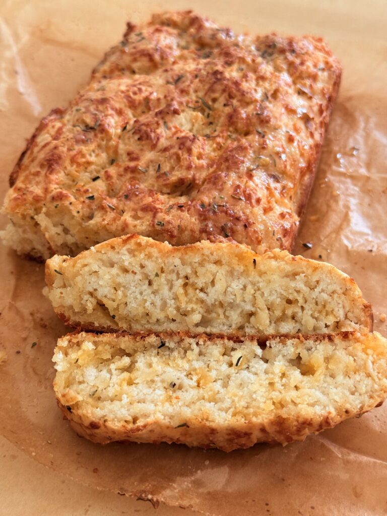 Sliced Bisquick Cheese and garlic loaf on brown parchment paper on the counter.