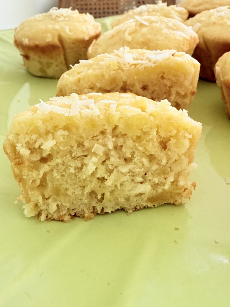 Hawaiian Banana Muffin cut in half, revealing the inside of the muffin on a lime green cake platter on the counter.