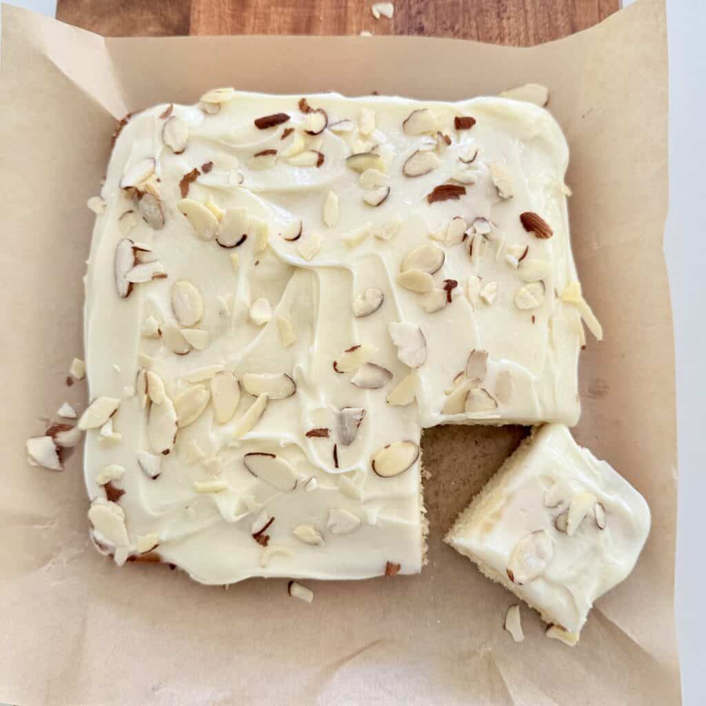 Almond Afternoon Cake on parchment paper on a brown cutting board.