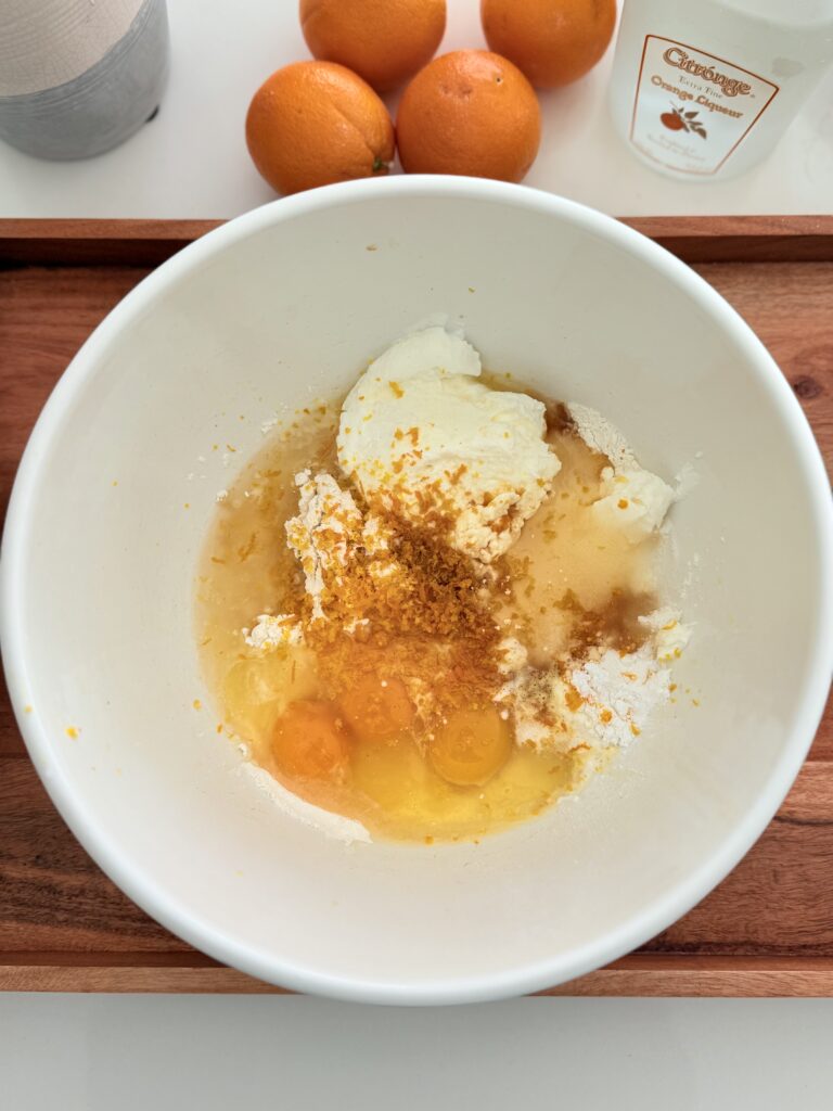 All the ingredients in a large white mixing bowl on a brown tray on the counter.