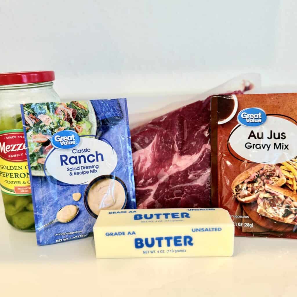 On the counter is the classic ranch salad dressing dry mix in a package, gravy mix in a package the unsalted butter, the 2.25 pound chuck roast and the jar of peppers and juice.