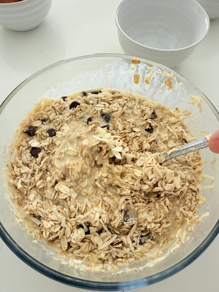 Mixing dry ingredients with wet ingredients in a glass bowl on the counter.