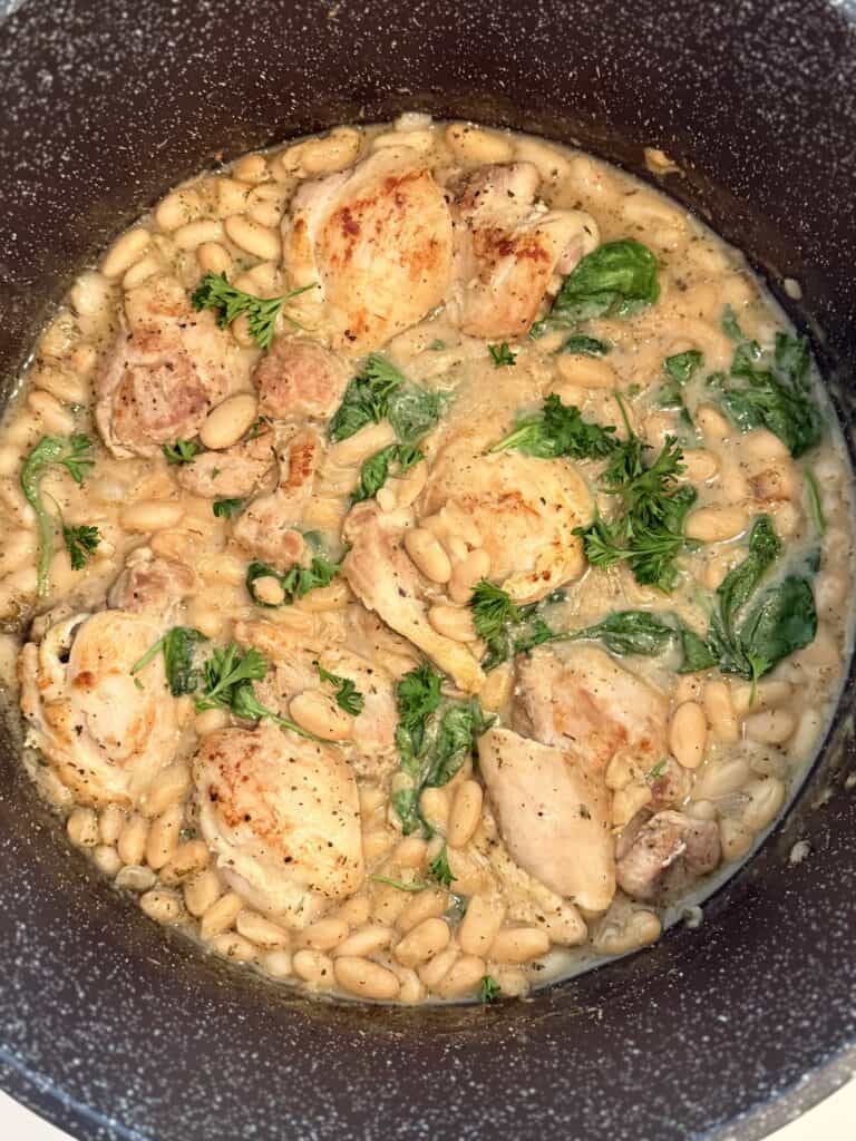 Herb de Provence chicken thighs with creamy white bean sauce on a brown cutting board on the counter.