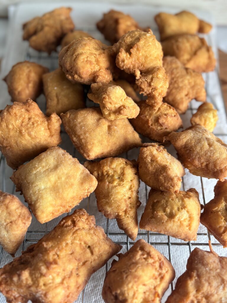 fried beignets cooling on a wire rack