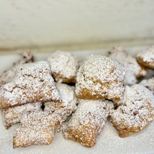 fried beignets sprinkled with powdered sugar on a plate