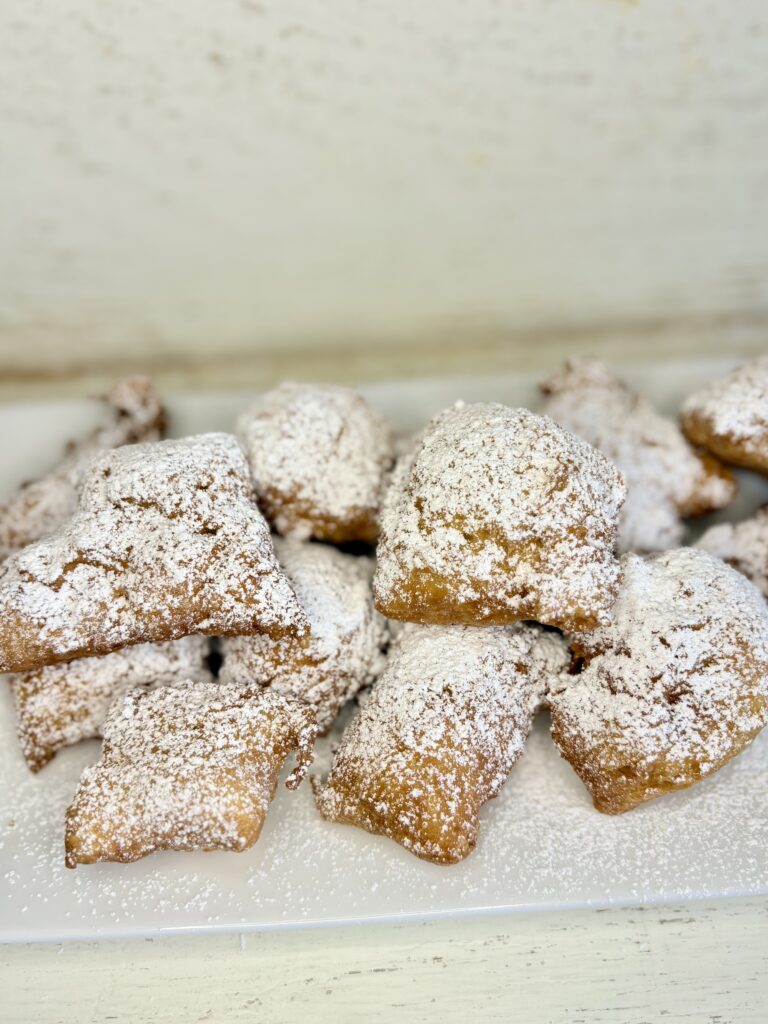 fried beignets sprinkled with powdered sugar on a plate