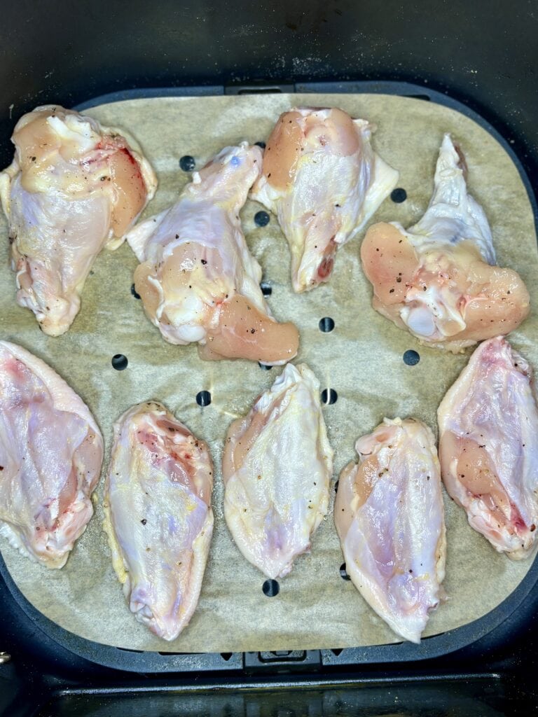 raw chicken wing pieces in an air fryer basket