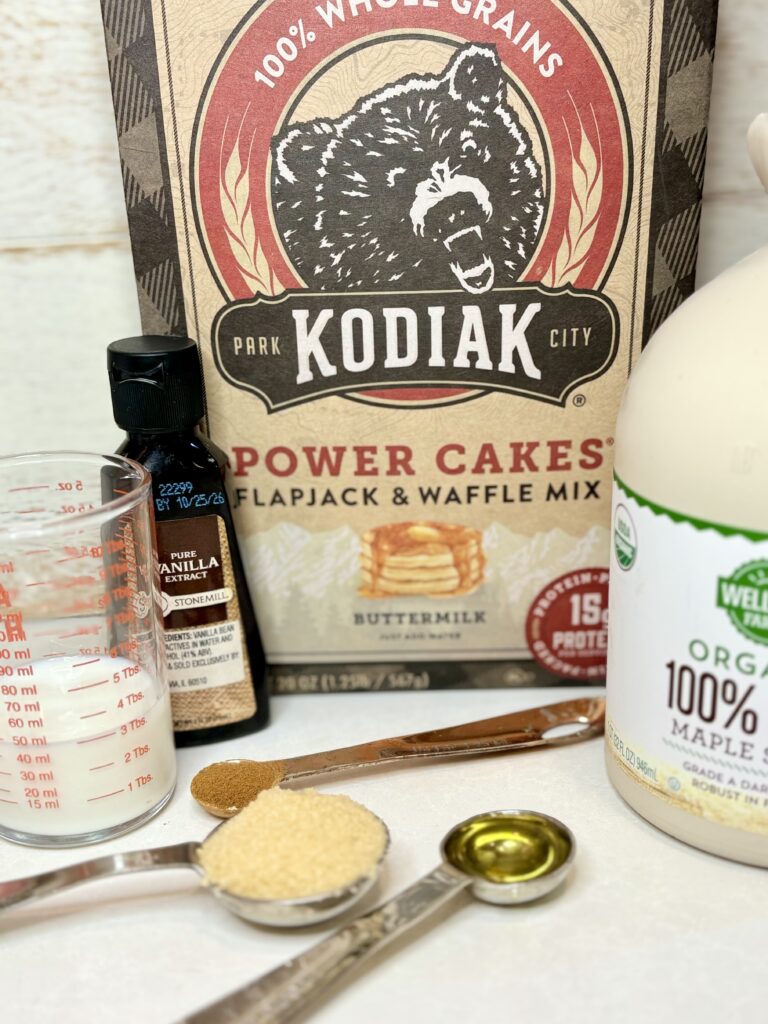 Kodiak mix, vanilla extract, milk, vanilla, maple syrup, brown sugar, oil, and cinnamon on a counter