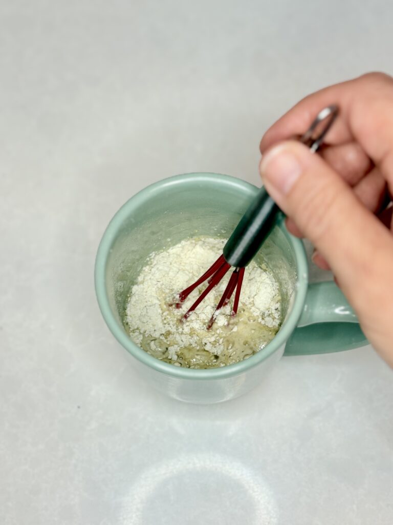 a whisk stirring dry and wet ingredients together in a mug