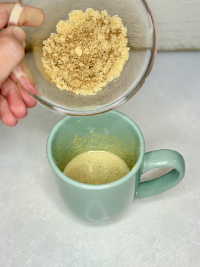 cinnamon brown sugar topping being added to batter in a mug