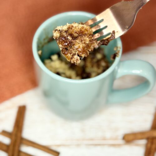 cooked cinnamon streusel muffin in a mug with a bite on a fork