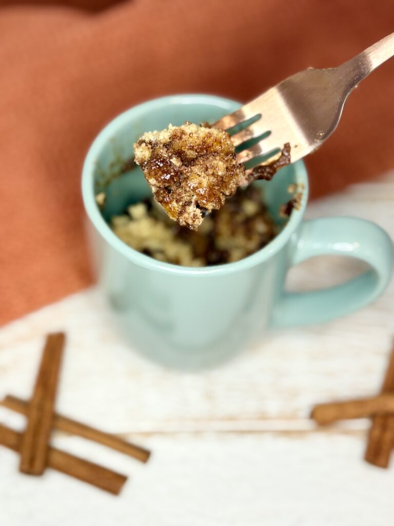 cooked cinnamon streusel muffin in a mug with a bite on a fork