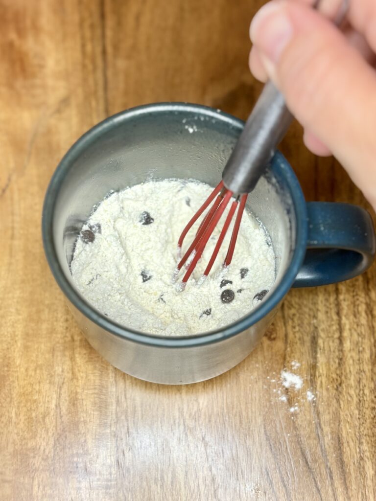 pancake mix and mini chocolate chips in a mug being whisked