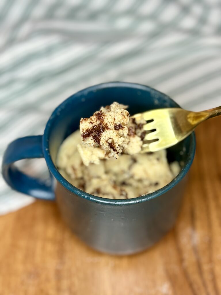 cooked chocolate chip muffin in a mug with a fork scooping up a bite