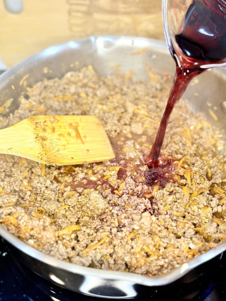 wine being poured into pan with ground beef mixture 