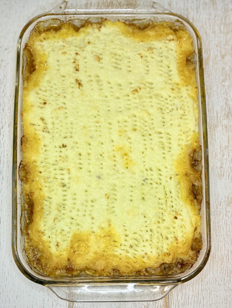 Baked Shepherd's pie in a pan on a wooden cutting board