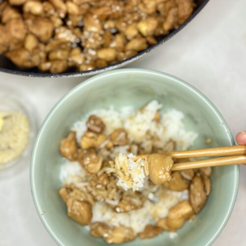 chicken and rice in a bowl being picked up with chopsticks next to a pan of chicken teriyaki