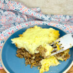 a serving of shepherd's pie on a plate next to a towel