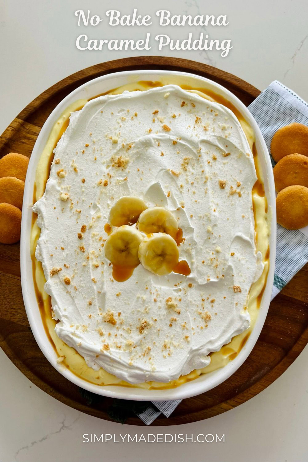 Creamy no-bake banana caramel pudding topped with sliced bananas and crushed cookies in an oval dish, served on a wooden tray with side cookies, perfect for easy, delicious dessert recipes.