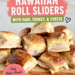 Baked Hawaiian Roll Sliders with ham, turkey, and cheese stacked on a wooden board, showcasing golden-brown crust and melted cheese.