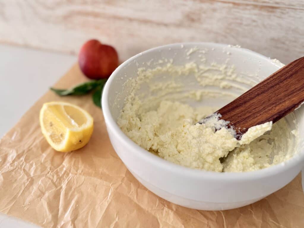 Whipped feta in a white mixing bowl on parchment paper on the counter.