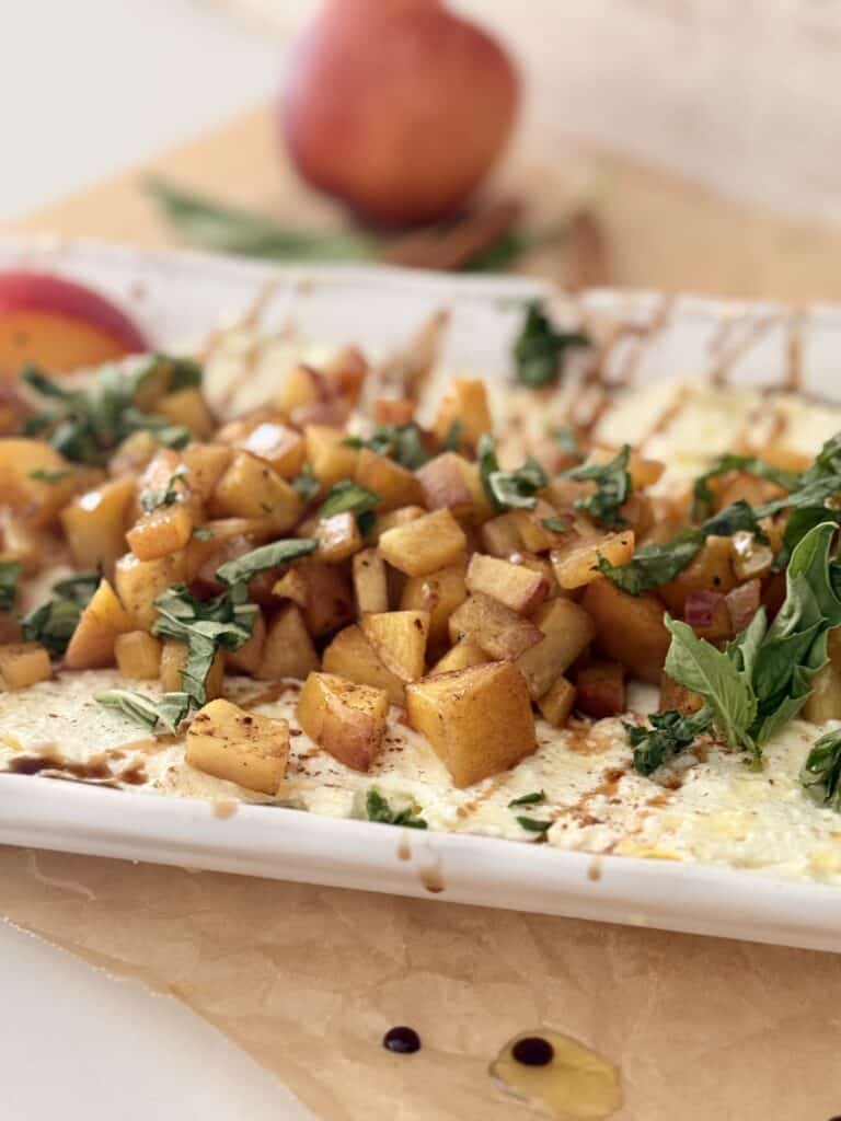 Whipped feta with roasted nectarines on a white platter on the counter.