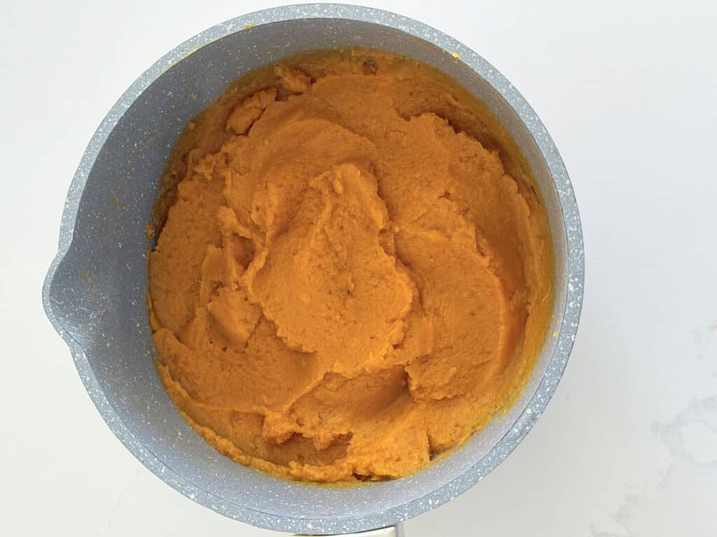 Mashed sweet potatoes in a pot on the counter.