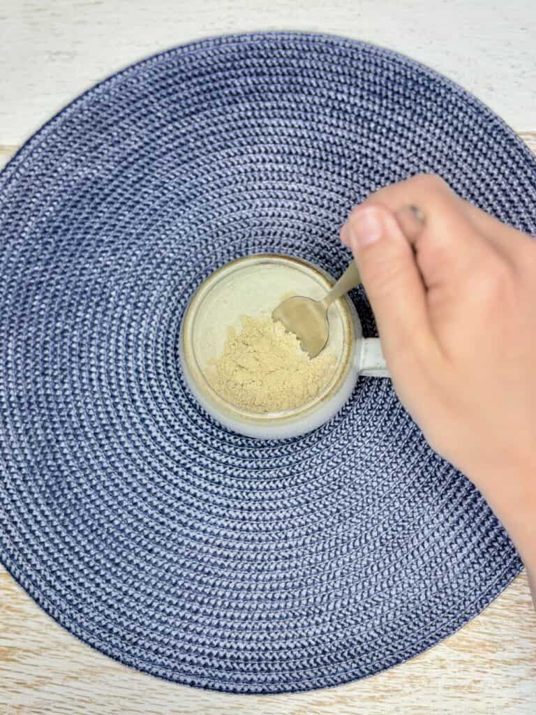 a hand using a spoon to stir together pancake mix and peanut butter powder