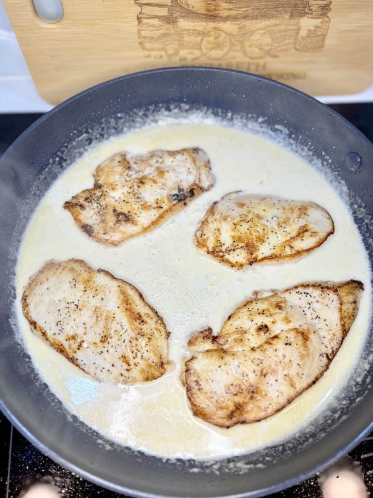 chicken in brandy cream sauce in a skillet on a stove top