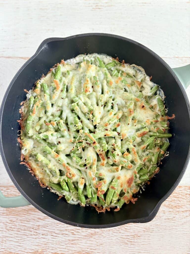 cooked cheesy green beans in a cast iron skillet